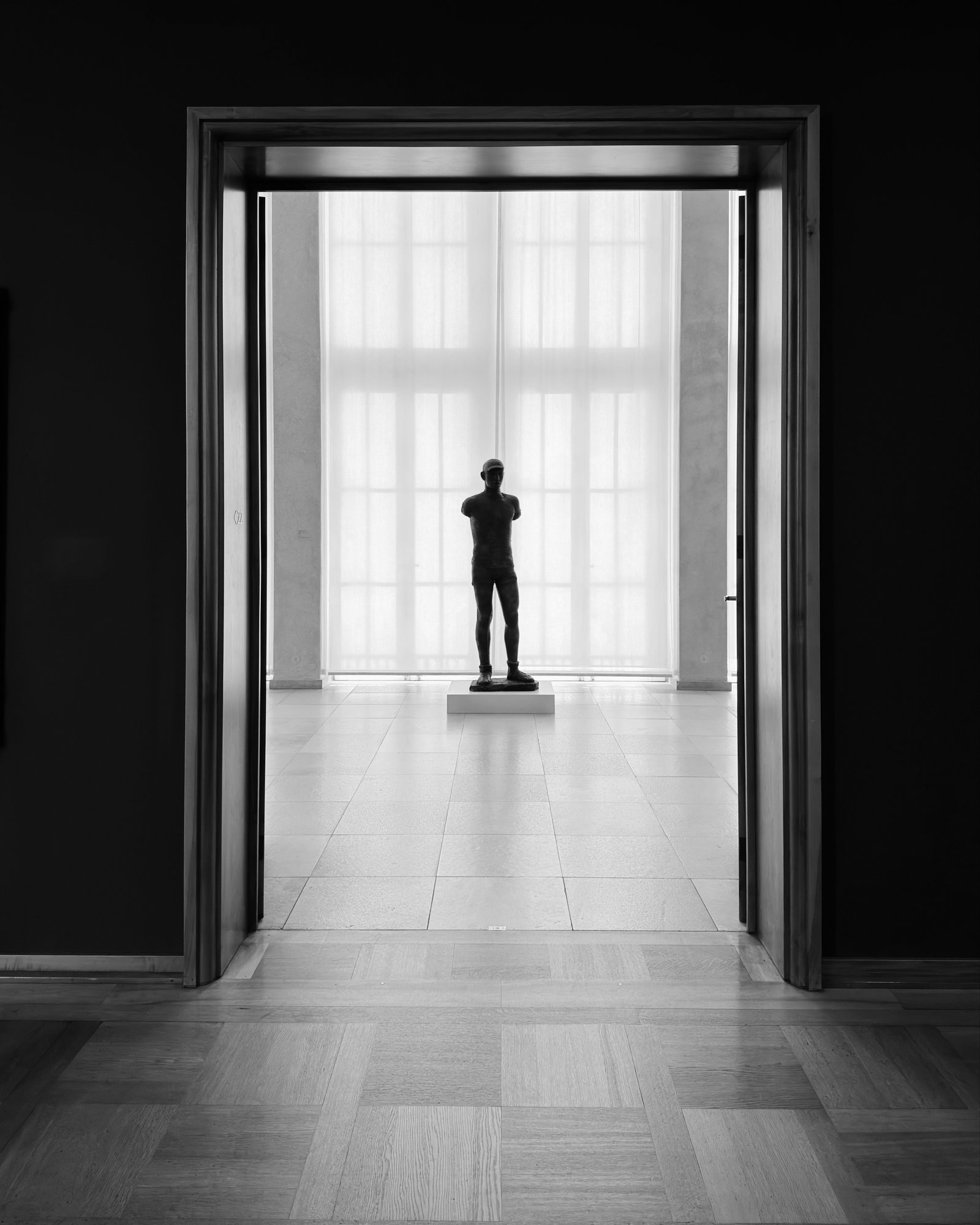 Bronze sculpture of a standing figure framed by a doorway